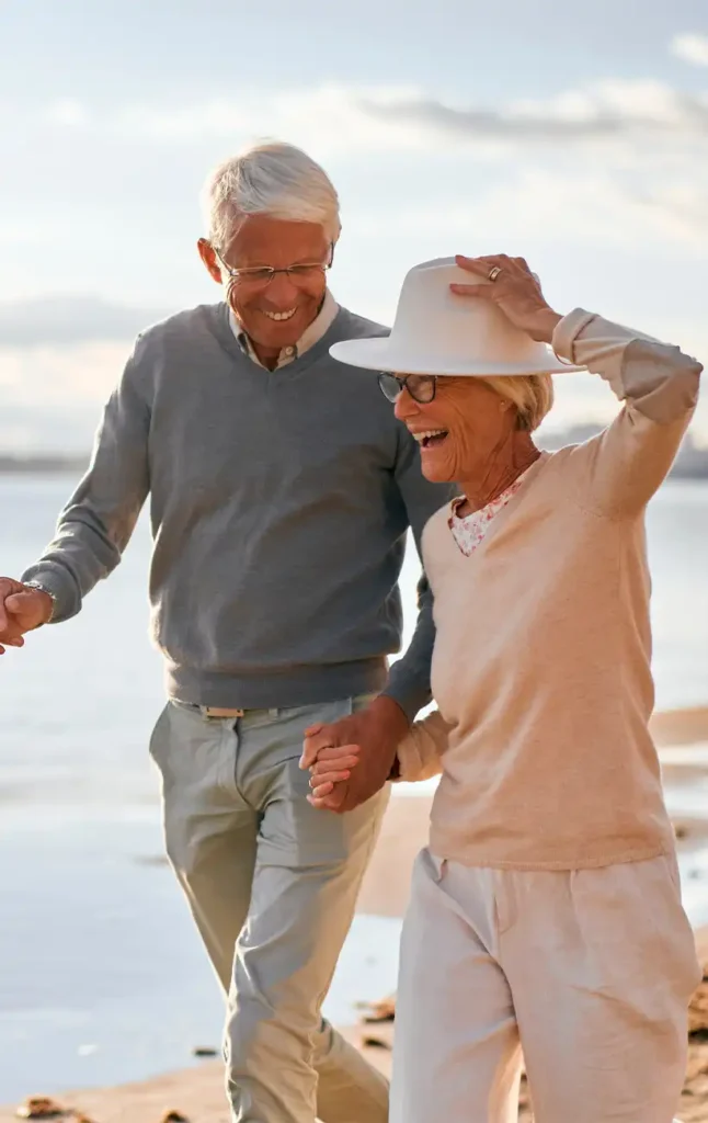 smiling retired couple walking on the beach together retirement strategies